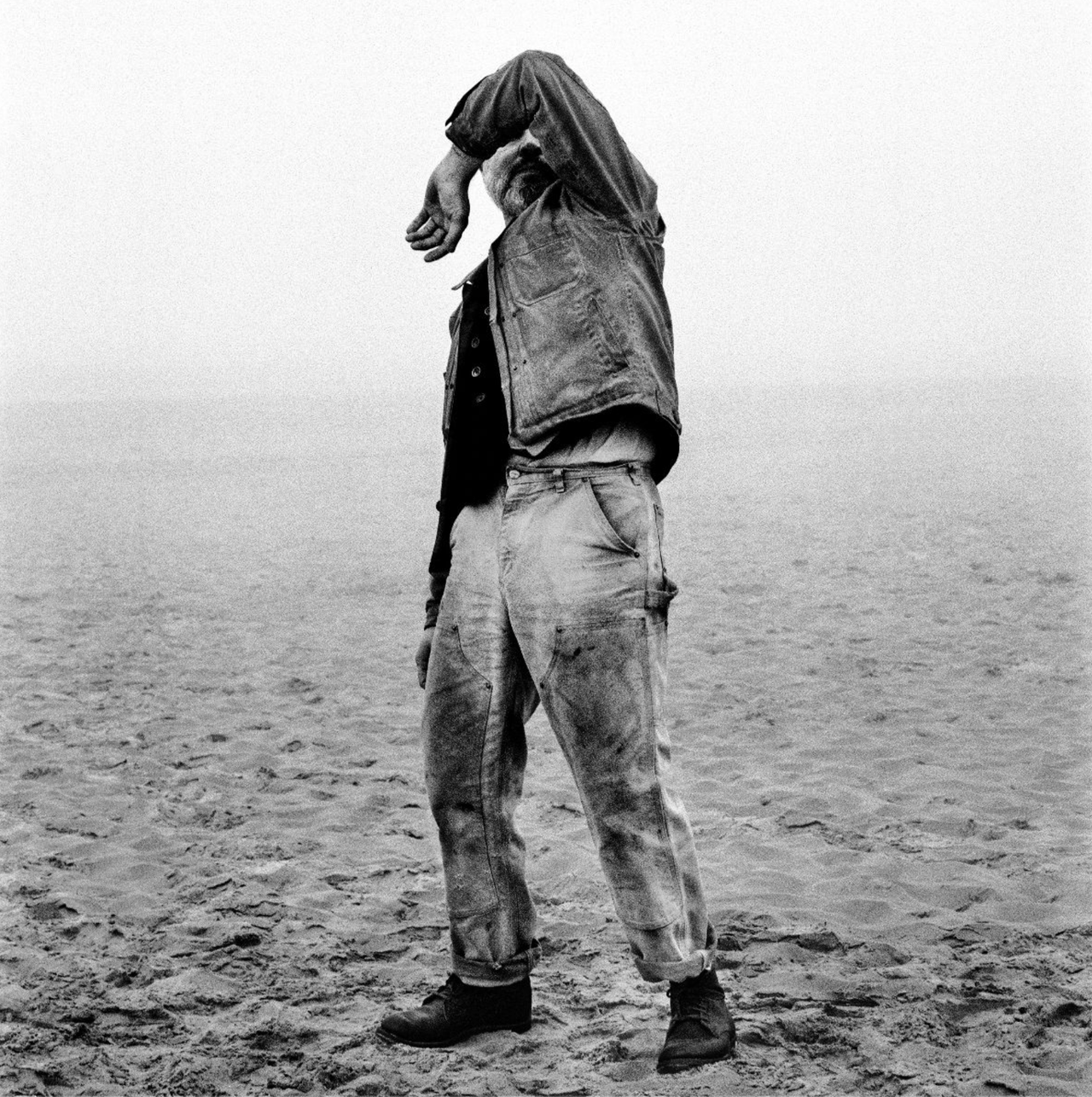Black and white cover art for The Tallest Man On Earth album featuring Kristian Matsson shielding his eyes in a denim jacket on a sandy field.